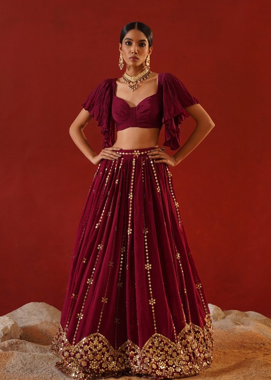 Woman wearing a maroon traditional outfit with gold details on a red background