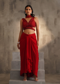 Woman wearing a red traditional outfit standing on stone steps with a textured wall background