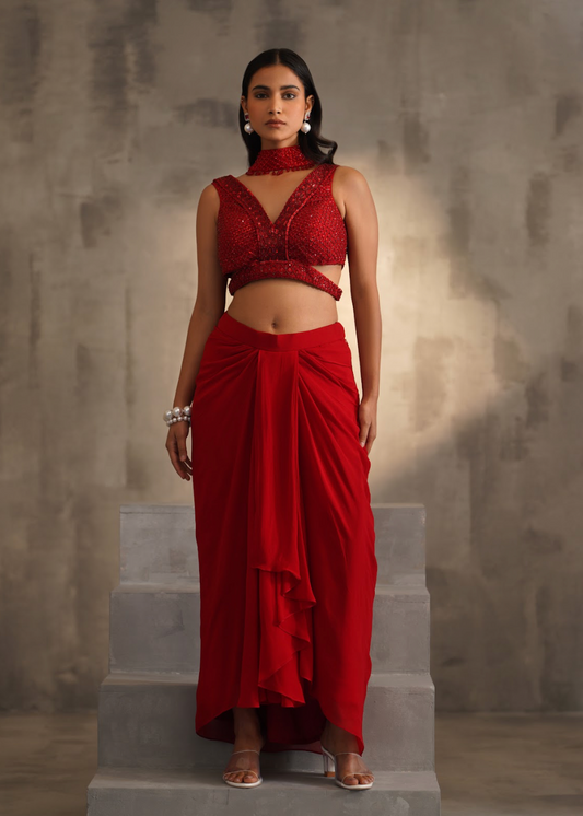 Woman wearing a red traditional outfit standing on stone steps with a textured wall background