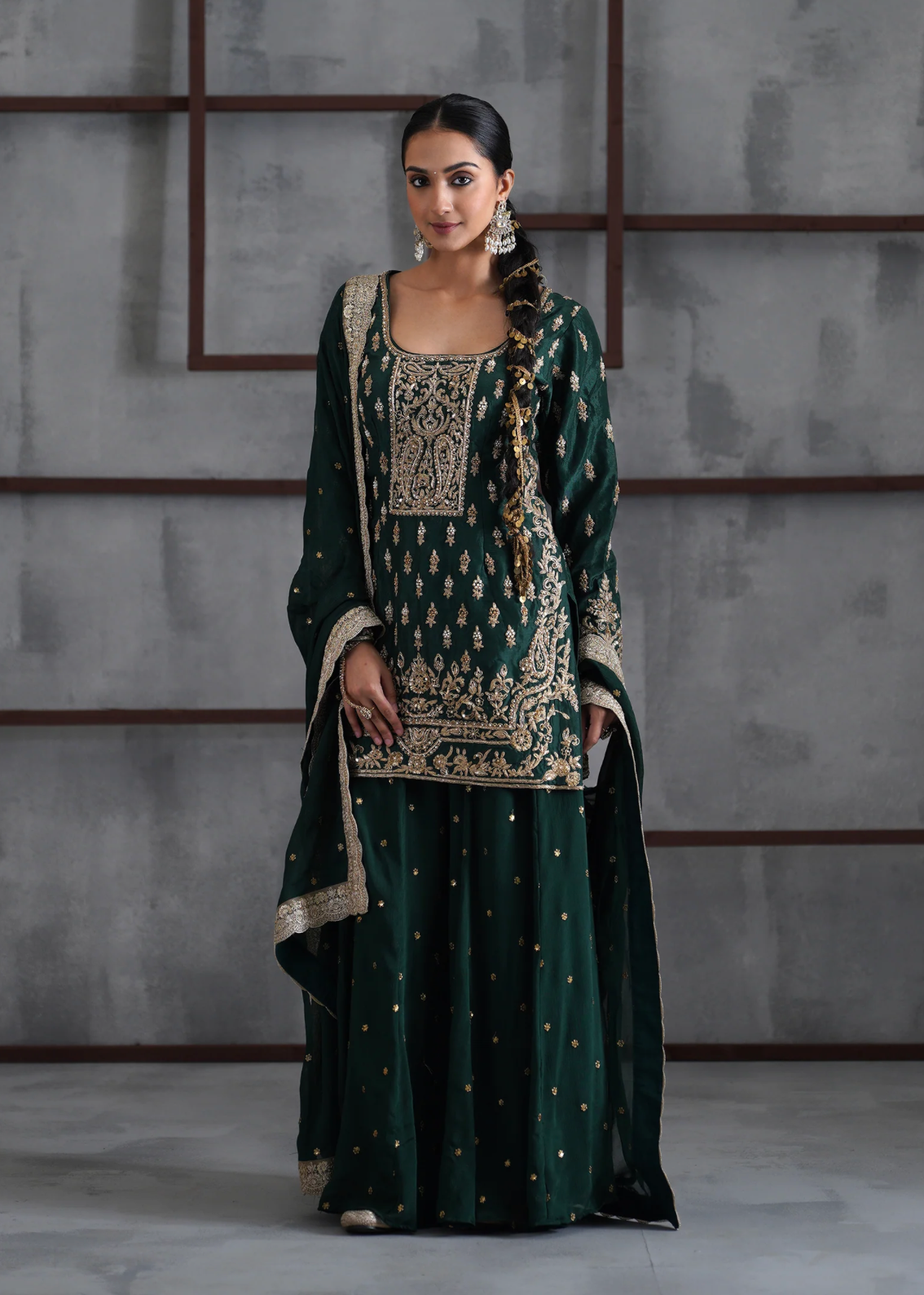 Woman wearing a traditional green and gold outfit against a gray background