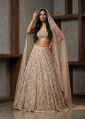 Woman in an elegant beige embroidered outfit with a matching dupatta against a neutral background