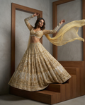 Woman in a gold embroidered lehenga standing in front of a mirror.