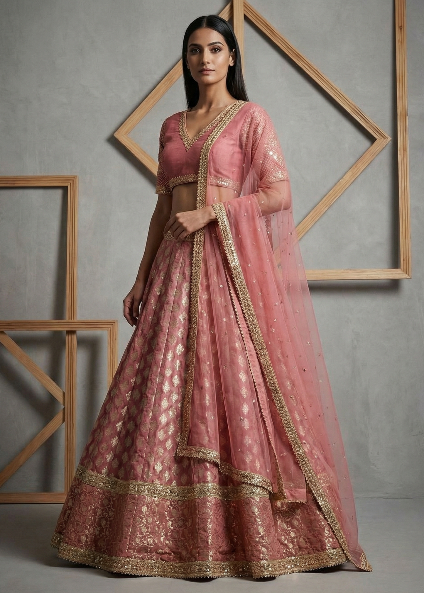 Woman wearing a pink traditional outfit with gold details against a gray background